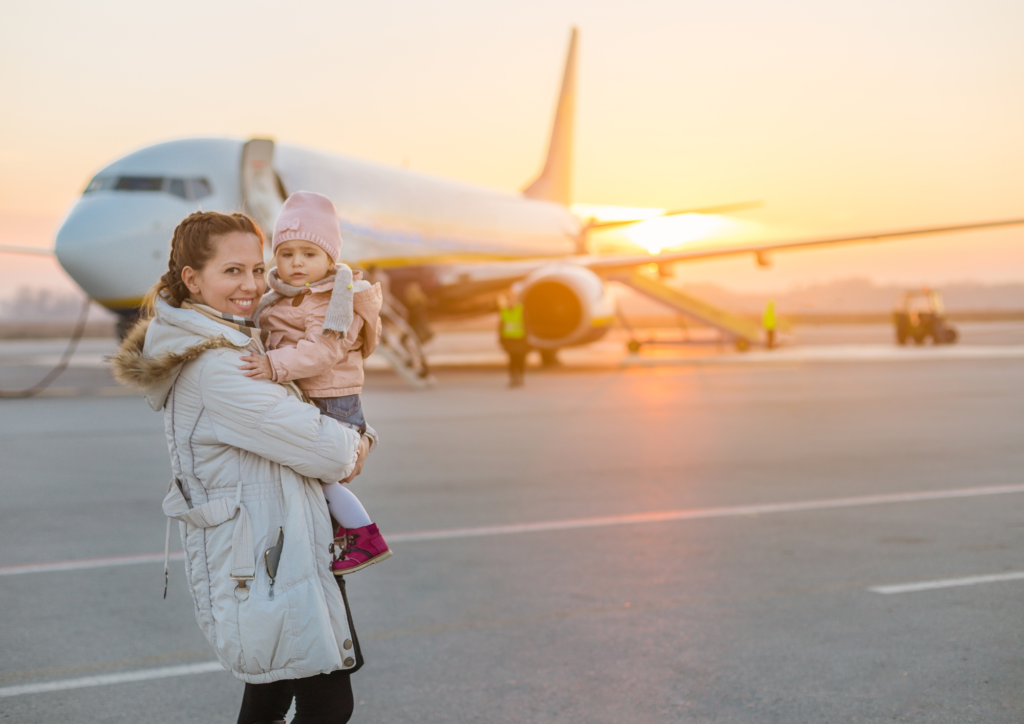 Mum and baby standing next to a plane