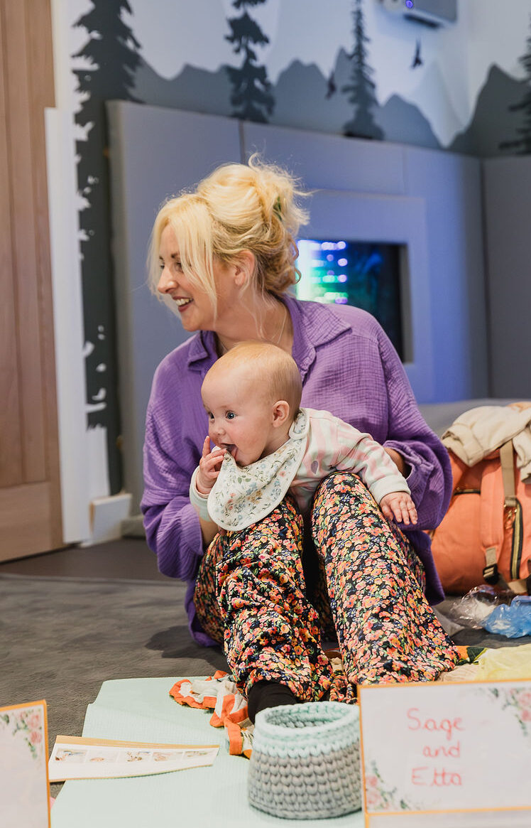 Baby in tummy time on her mums knee