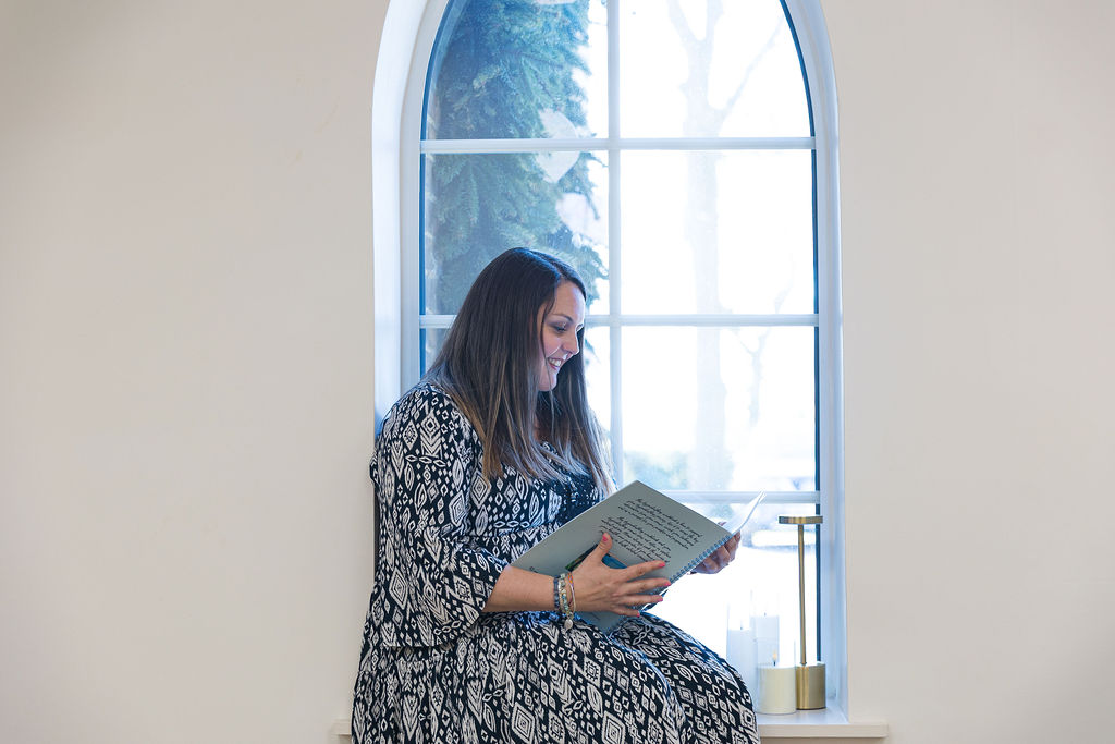 Woman sitting by a window reflecting, representing teaching birth and pregnancy education